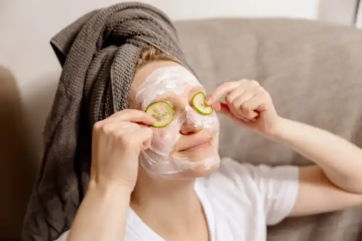 Mujer relajándose con mascarilla facial y rodajas de pepino, momento de autocuidado