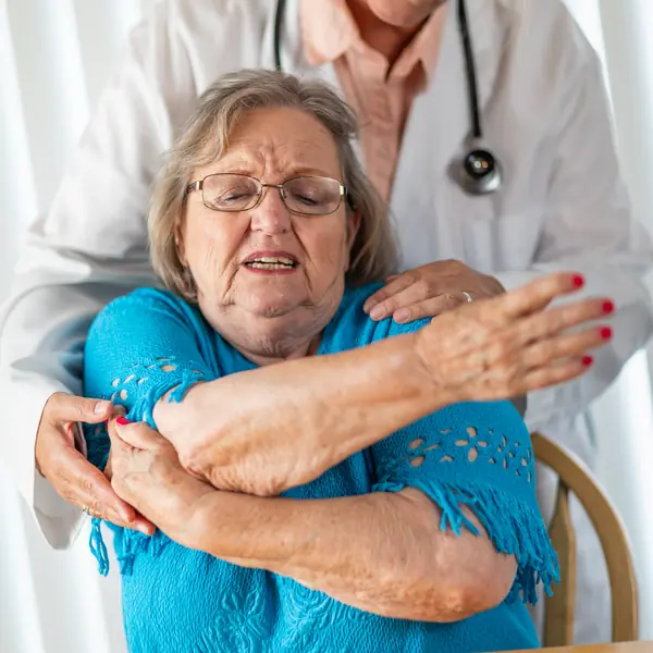 Médico revisa el hombro de una señora mayor durante una consulta