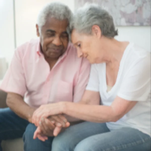 Pareja de adultos mayores sentados juntos, tomados de la mano